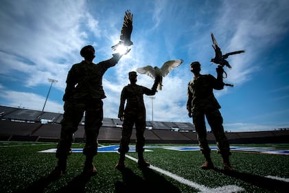 Cadet 2nd Class Kayla Steiner, center, handler of Nova, the newly named 15-week-old full white-phase Gyrfalcon, displays the new mascot of the U.S. Air Force Academy with Cadet 1st Class Seamus Kean, left, and Cadet 3rd Class Sierra Hillard, right.