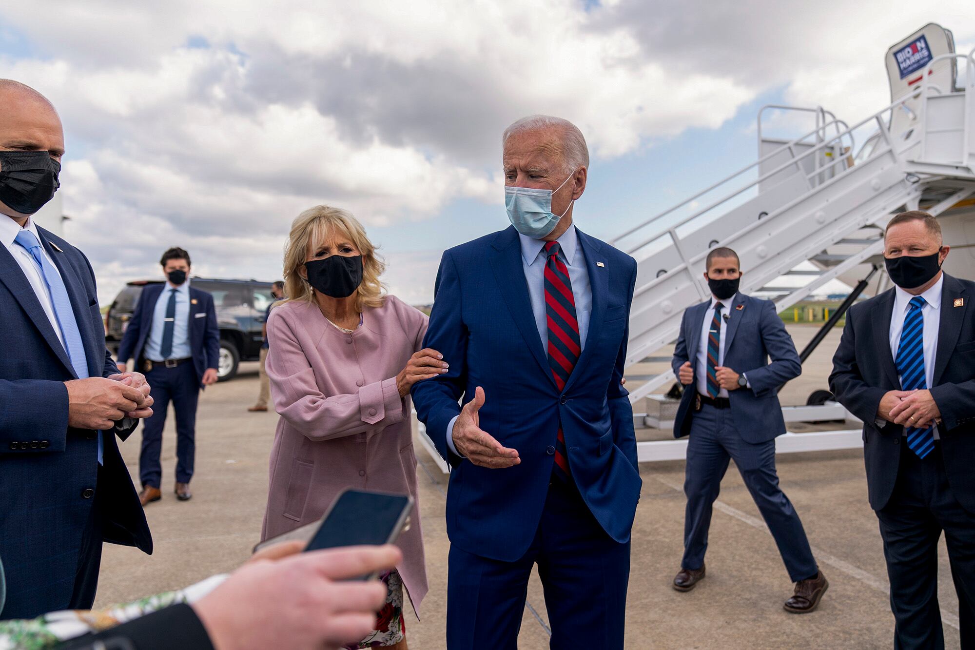 Jill Biden moves her husband, Democratic presidential candidate former Vice President Joe Biden, back from members of the media as he speaks outside his campaign plane in New Castle, Del., on Oct. 5, 2020.