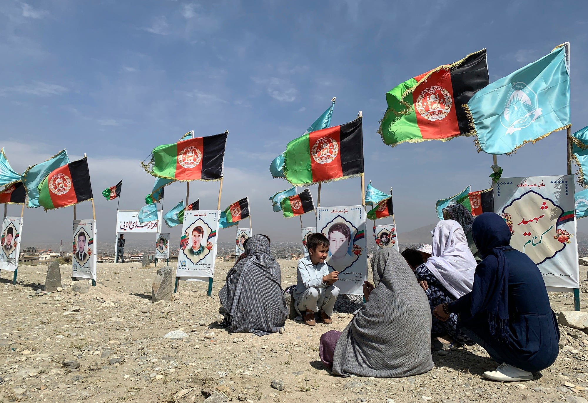 In this Sept 14, 2020, file photo, families and friends of students who were killed in local conflicts gather at the graves of their relatives, adorned with their pictures, on the outskirts of Kabul, Afghanistan.