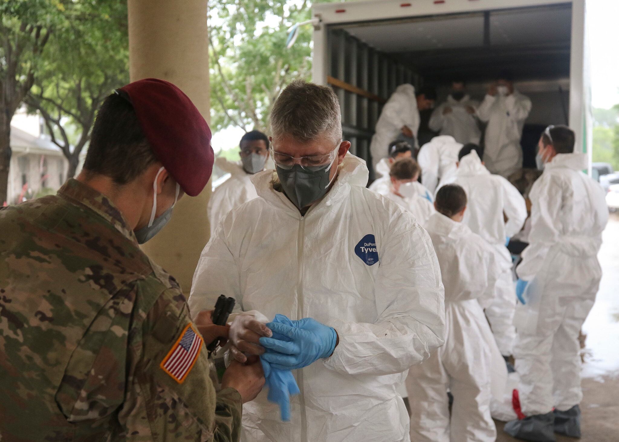 Army National Guard Spc. Joel Mendoza assists Capt. Patrick Couch with donning personal protective gear in preparation for disinfecting the West Oaks Nursing and Rehabilitation Center in Austin, Texas, May 12, 2020.