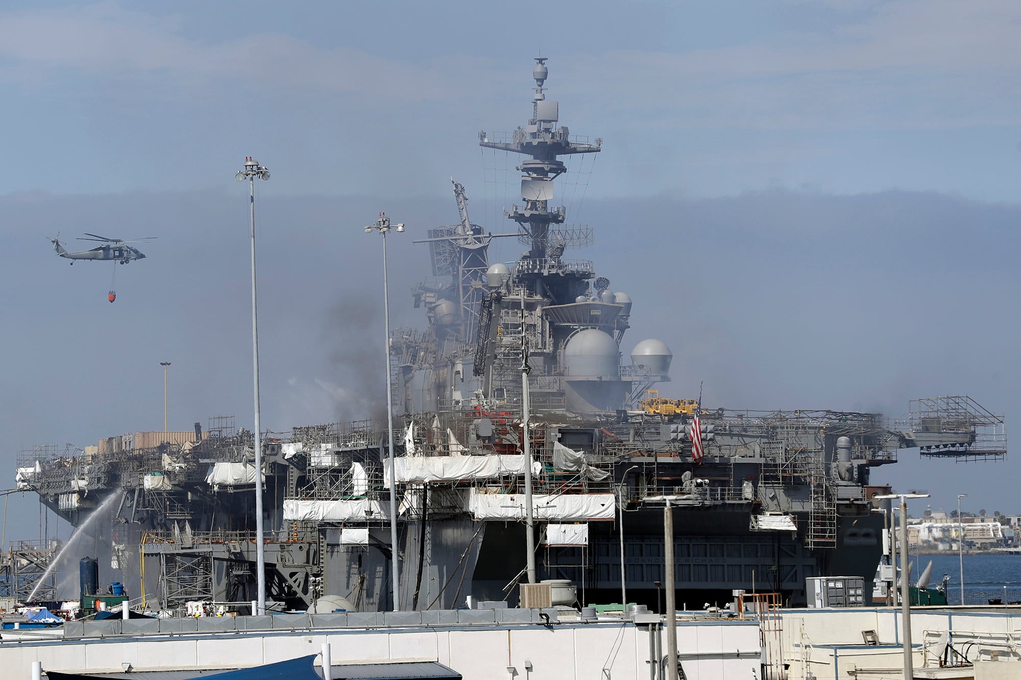 A helicopter carrying water passes the USS Bonhomme Richard on July 14, 2020, in San Diego.