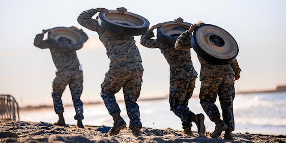 Marines with 1st Marine Division carry track wheels during the Amphibious Combat Endurance Test on Marine Corps Base Camp Pendleton, Calif., Jan. 15, 2021.