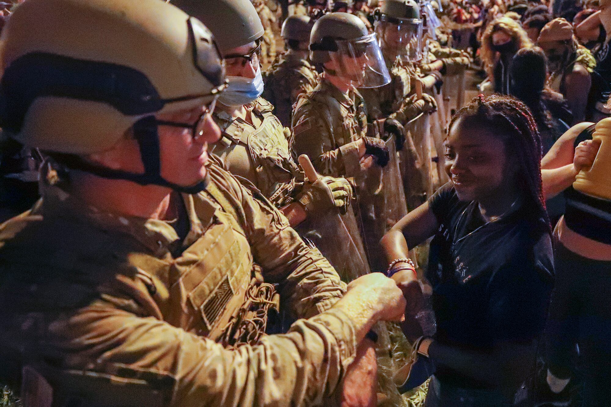 A Utah National Guard solider fist-bumps with a demonstrator as protests over the death of George Floyd continue, Wednesday, June 3, 2020, near the White House in Washington.