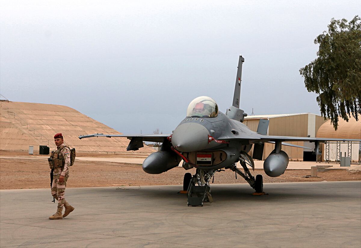 an Iraqi army soldier stand guard near a U.S.- made Iraqi Air Force F-16 fighter jet at the Balad Air Base, Iraq.