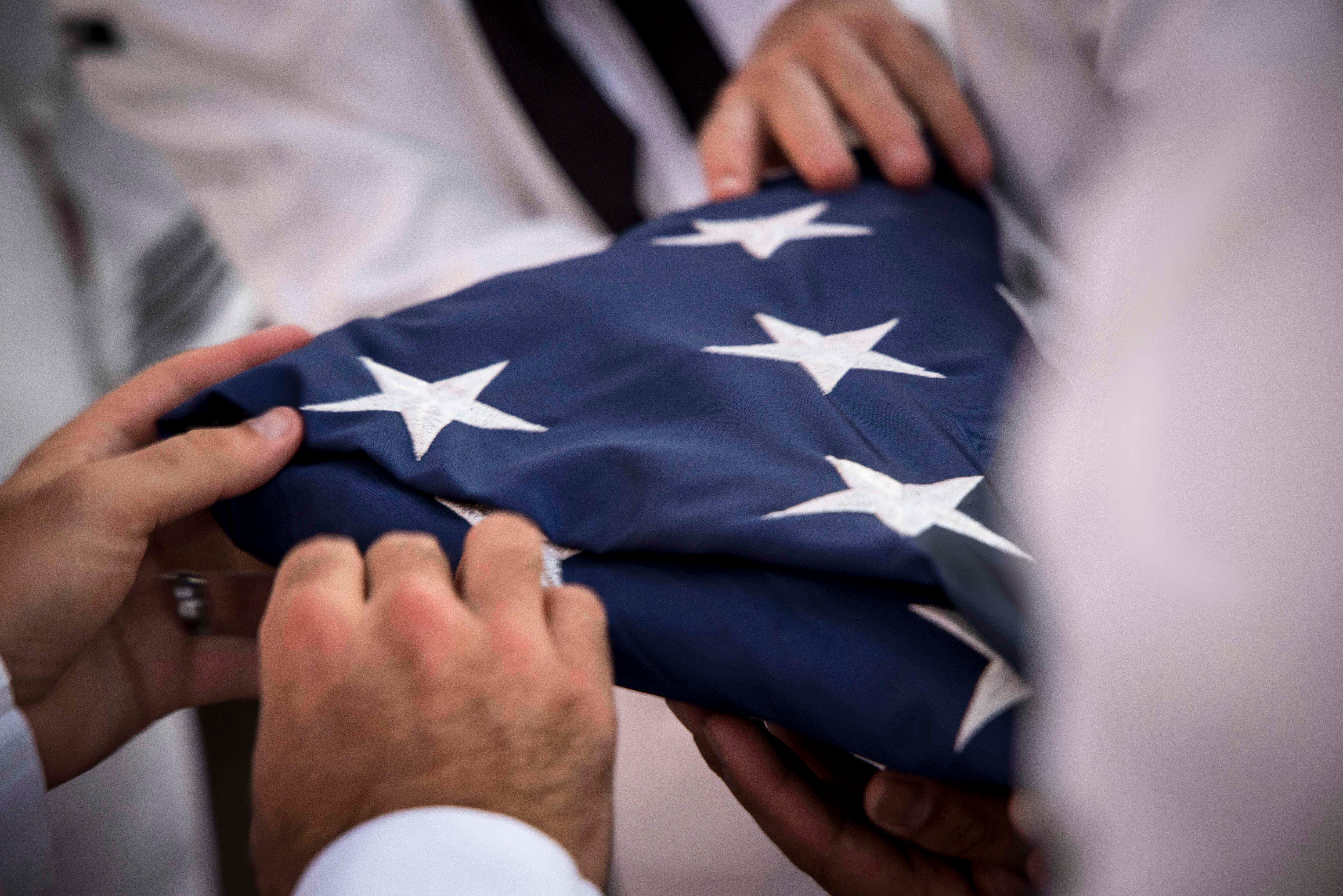 Chief Petty Officer selectees fold the flag as part of a colors detail on Aug. 19, 2019, during CPO Heritage Week in Boston.