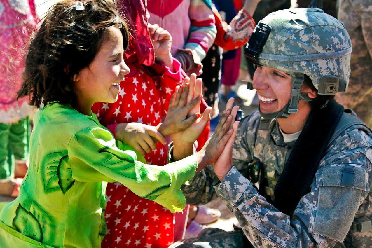 U.S. Army Sgt. Stephanie Tremmel, right, with the 86th Special Troops Battalion, 86th Infantry Brigade Combat Team, interacts with an Afghan child while visiting Durani, Afghanistan, Nov. 1, 2010.