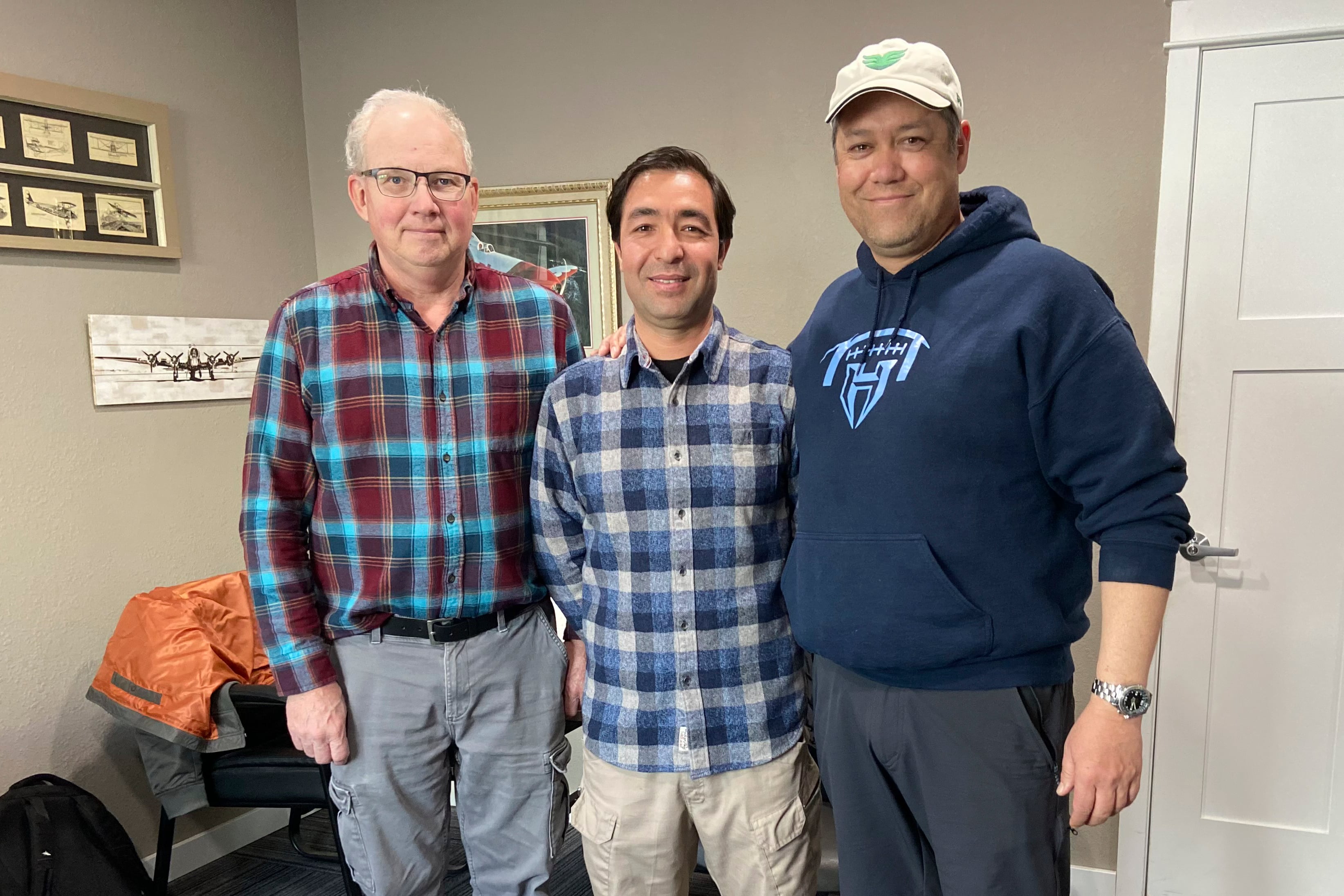 In this photo provided by Nikki Chung, Mohammad Hussain Musawi, center, stands with his flight instructor, left, and Darin Chung, co-founder of the Afghan American Development Group, a nonprofit that helps former Afghan military aviation personnel with refugee resettlement assistance in the U.S., at a flight hangar in Independence, Ore. on April 7, 2023.