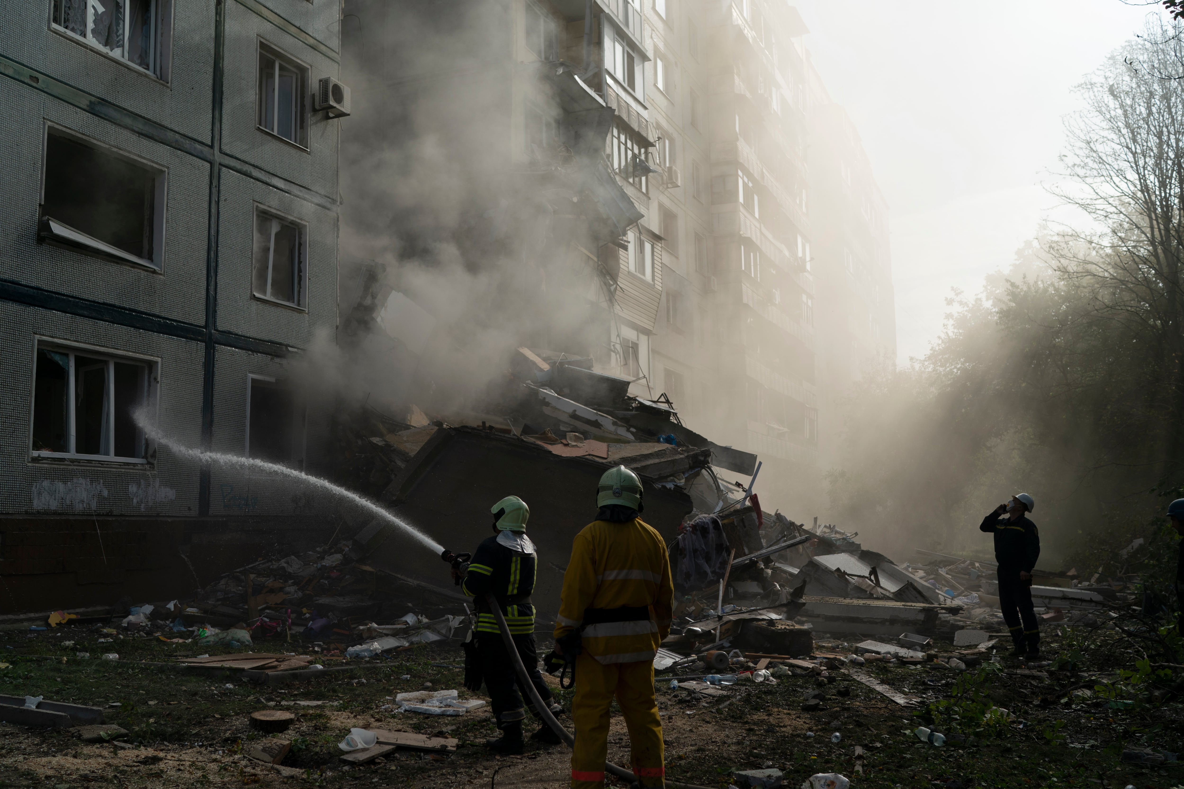 Firefighters work at the scene where a residential building was heavily damaged after a Russian attack in Zaporizhzhia, Ukraine, Sunday, Oct. 9, 2022.