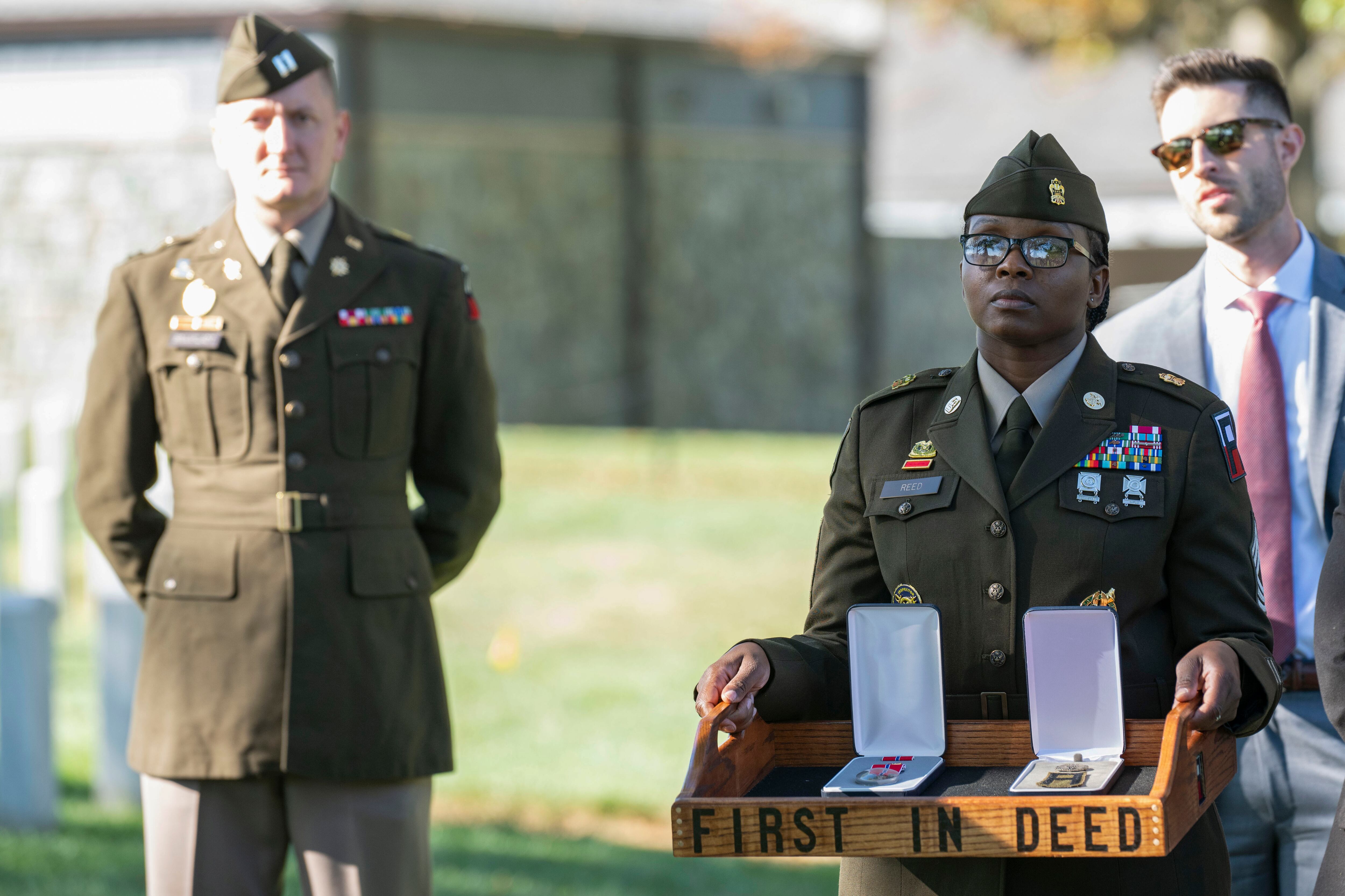 A soldier, right, holds the Bronze Star and Combat Medic Badge to be posthumously presented to Cpl. Waverly B. Woodson Jr. during a ceremony at Arlington National Cemetery on Tuesday, Oct. 11, 2023 in Arlington, Va.