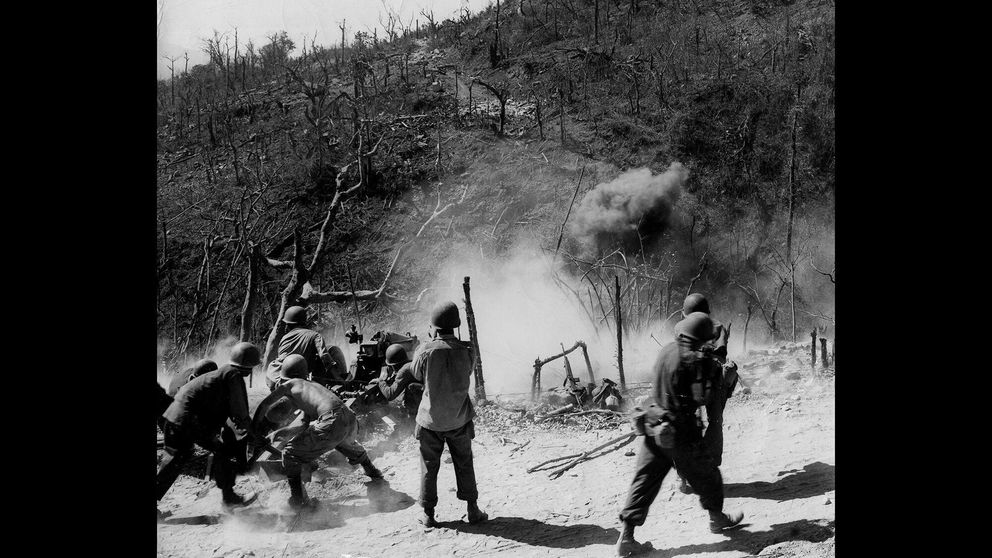 In this photo provided by the U.S. Army Signal Corps, this gun crew, part of a parachute artillery unit which dropped on the fortress island of Corregidor, is firing point-blank at a cave which the Japanese took over, March 3, 1945.