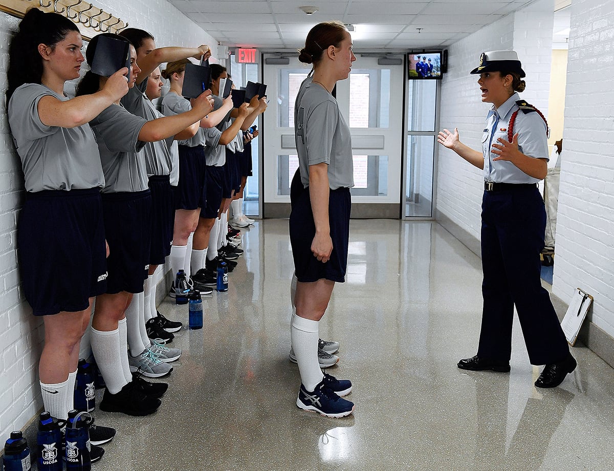 In this July 1, 2019, file photo, female swabs learn the positions of attention and parade rest while their male classmates get haircuts during the first day of a seven-week orientation for the Class of 2023 at the U.S. Coast Guard Academy in New London, Conn.