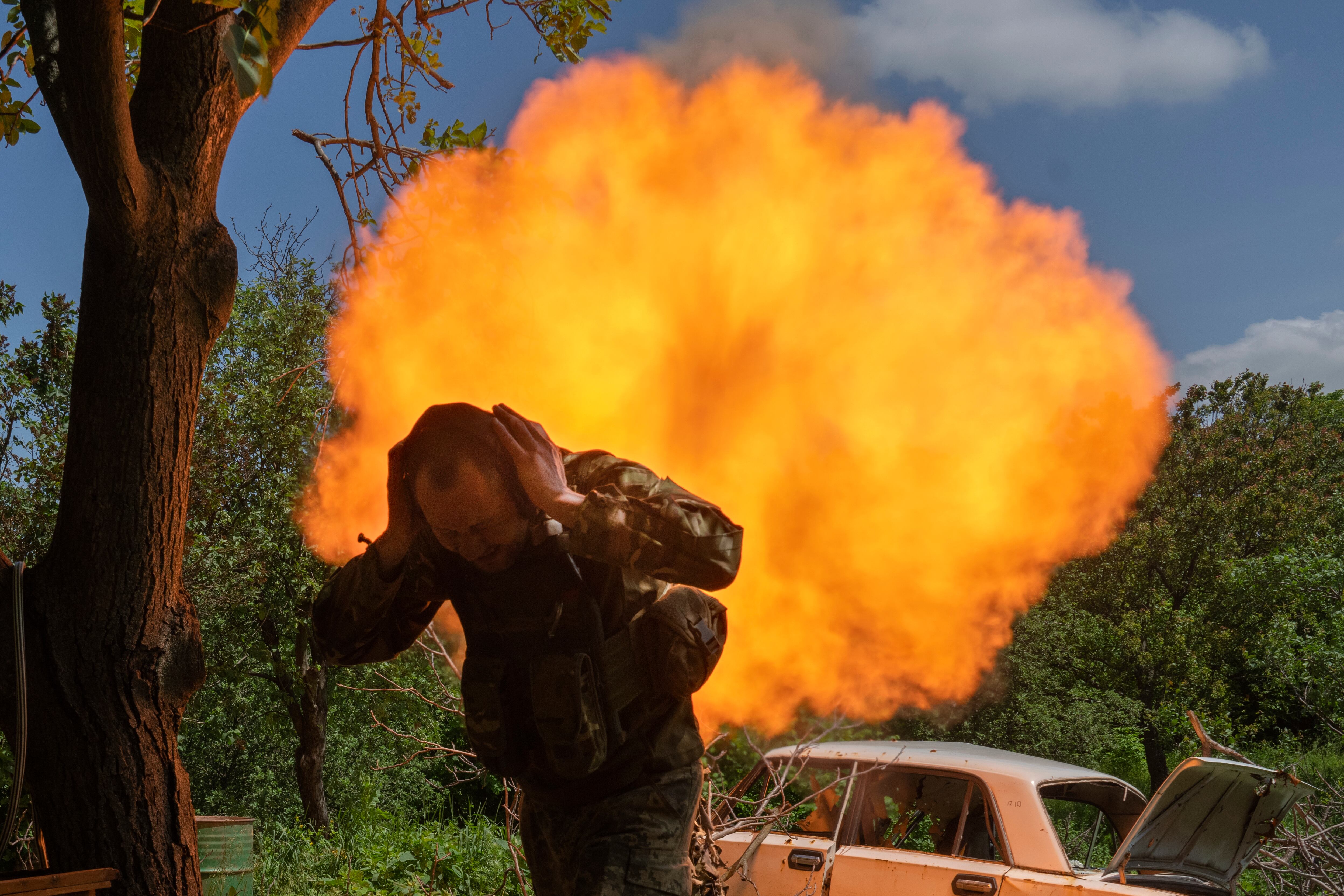 A Ukrainian soldier covers his ears while firing a mortar at Russian positions on the frontline near Bakhmut, Donetsk region, Ukraine, Monday, May 29, 2023.