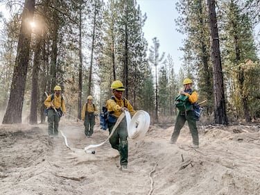 Oregon Army National Guard soldier Pfc. Iverson Hallers throws out a 100-foot roll of fire hose to complete a water supply line more than a mile long.