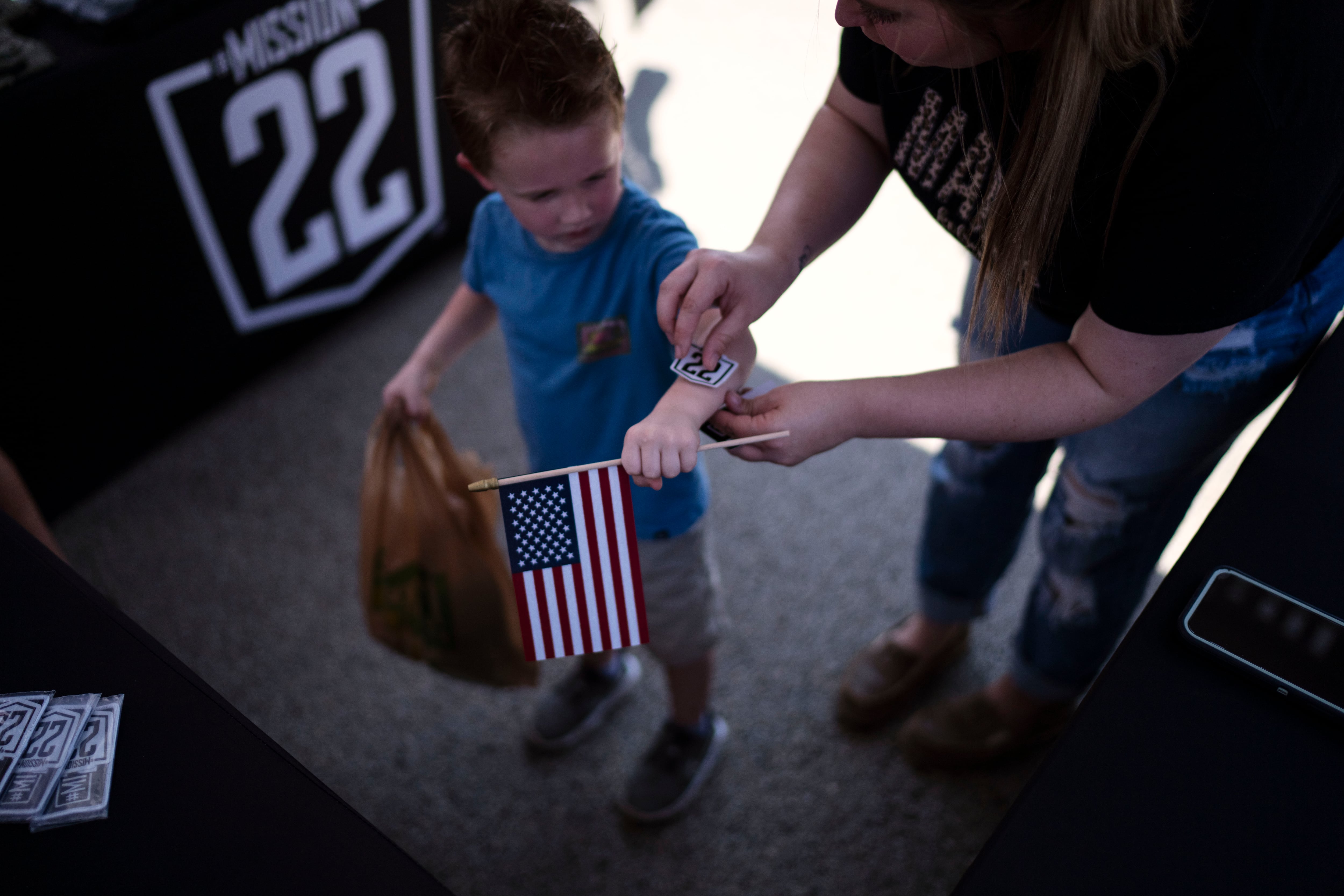 A child gets sticker from Mission 22, a nonprofit that is focused on ending military and veteran suicide, Saturday, June 10, 2023, at a festival in Jacksonville, Texas.