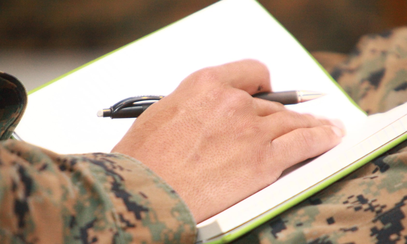 Closeup of military member's hand, taking notes in a journal