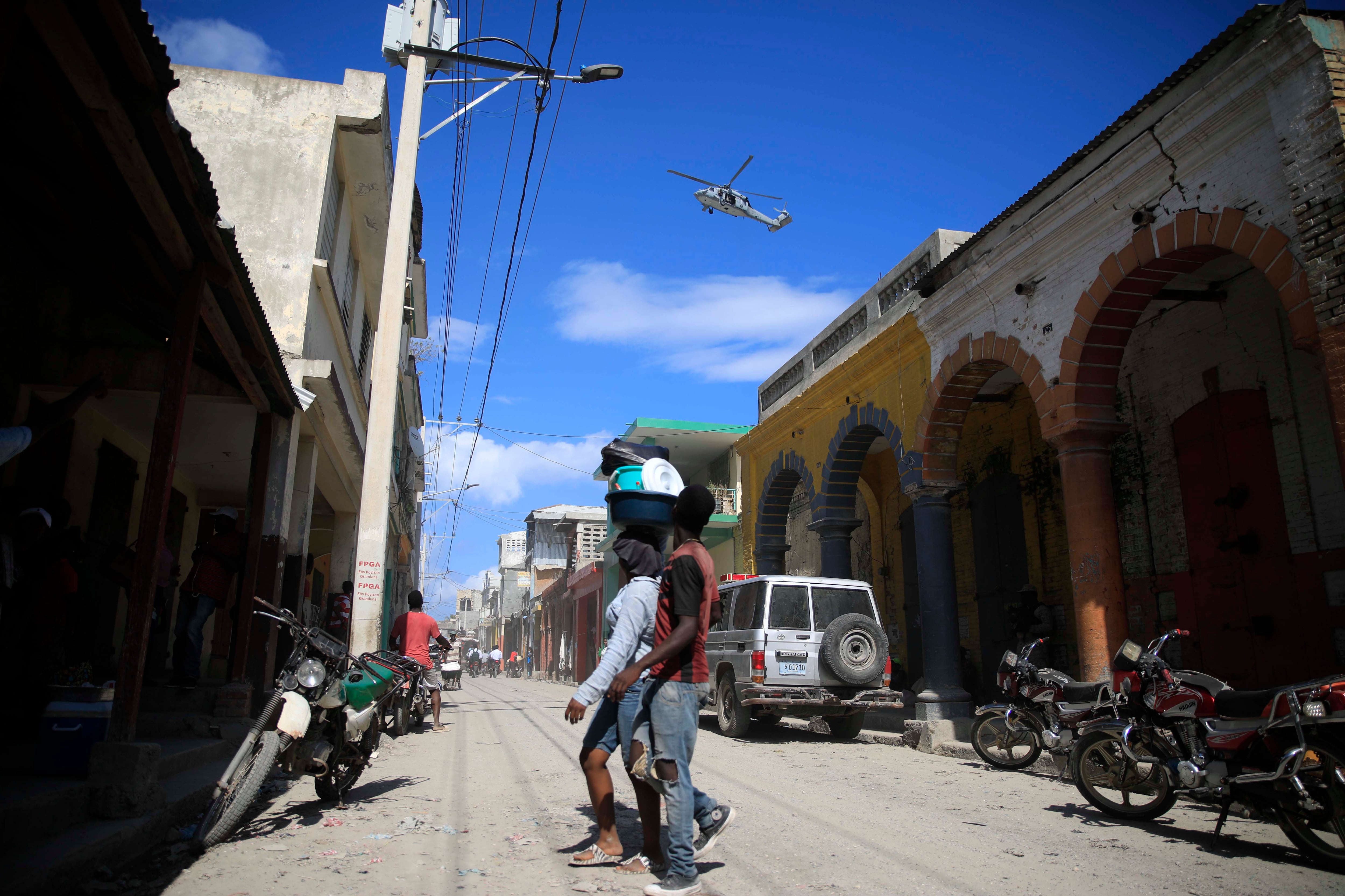 A USN helicopter flies overhead during a protest against the arrival of the USNS Comfort hospital ship in Jeremie, Haiti, Tuesday, Dec. 13, 2022.