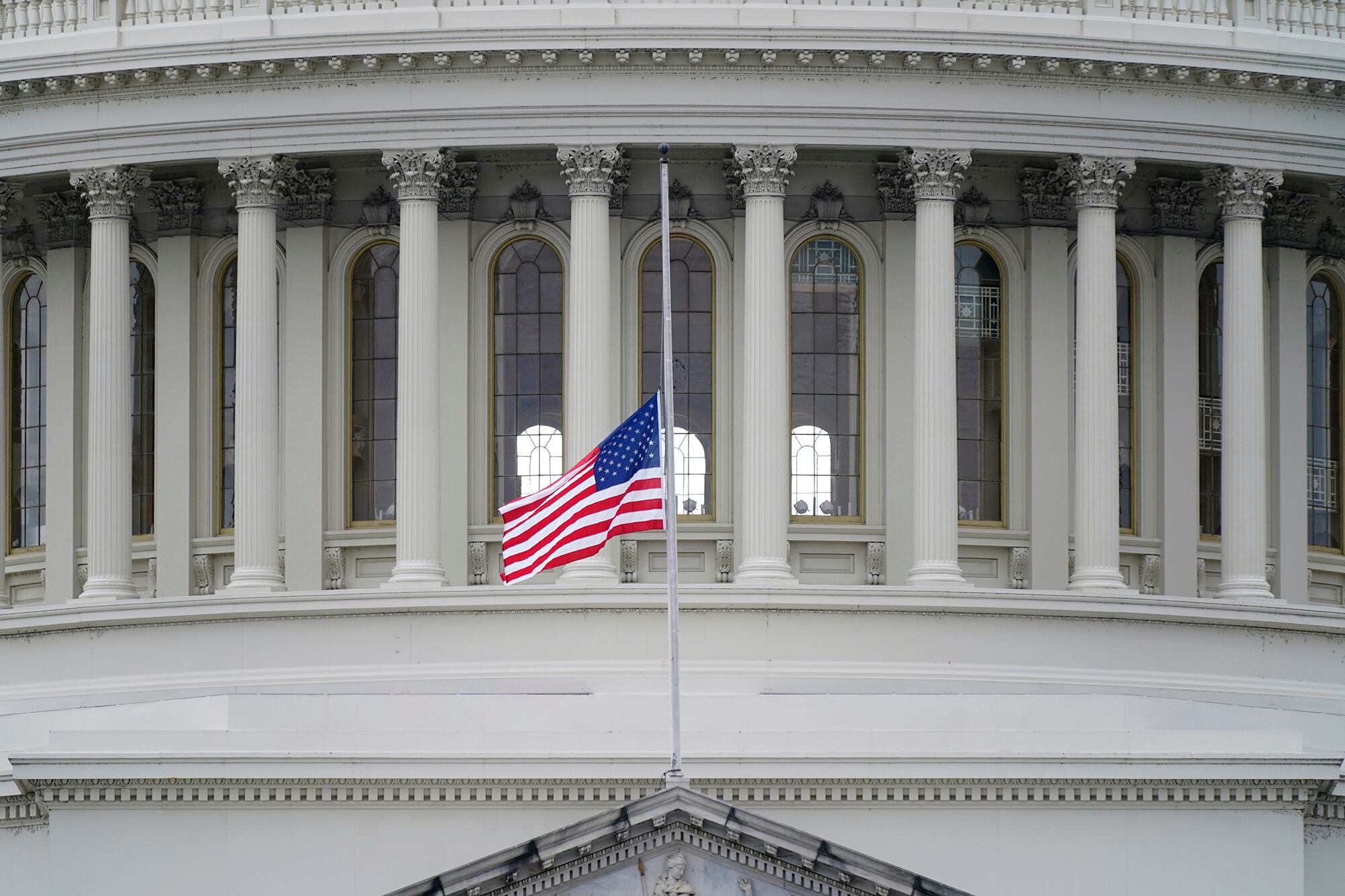 An American flag flies at half-staff in remembrance of U.S. Capitol Police Officer Brian Sicknick above the Capitol Building in Washington, Friday, Jan. 8, 2021.