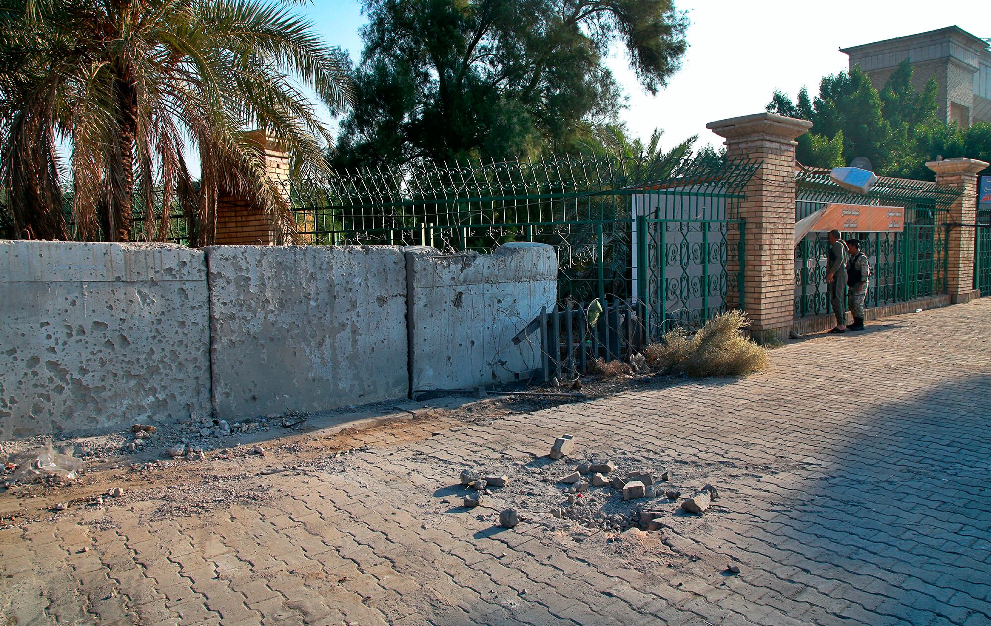 Security forces inspect the scene of the rocket attack at the gate of al-Zawra public park in Baghdad, Iraq, Nov. 18, 2020.