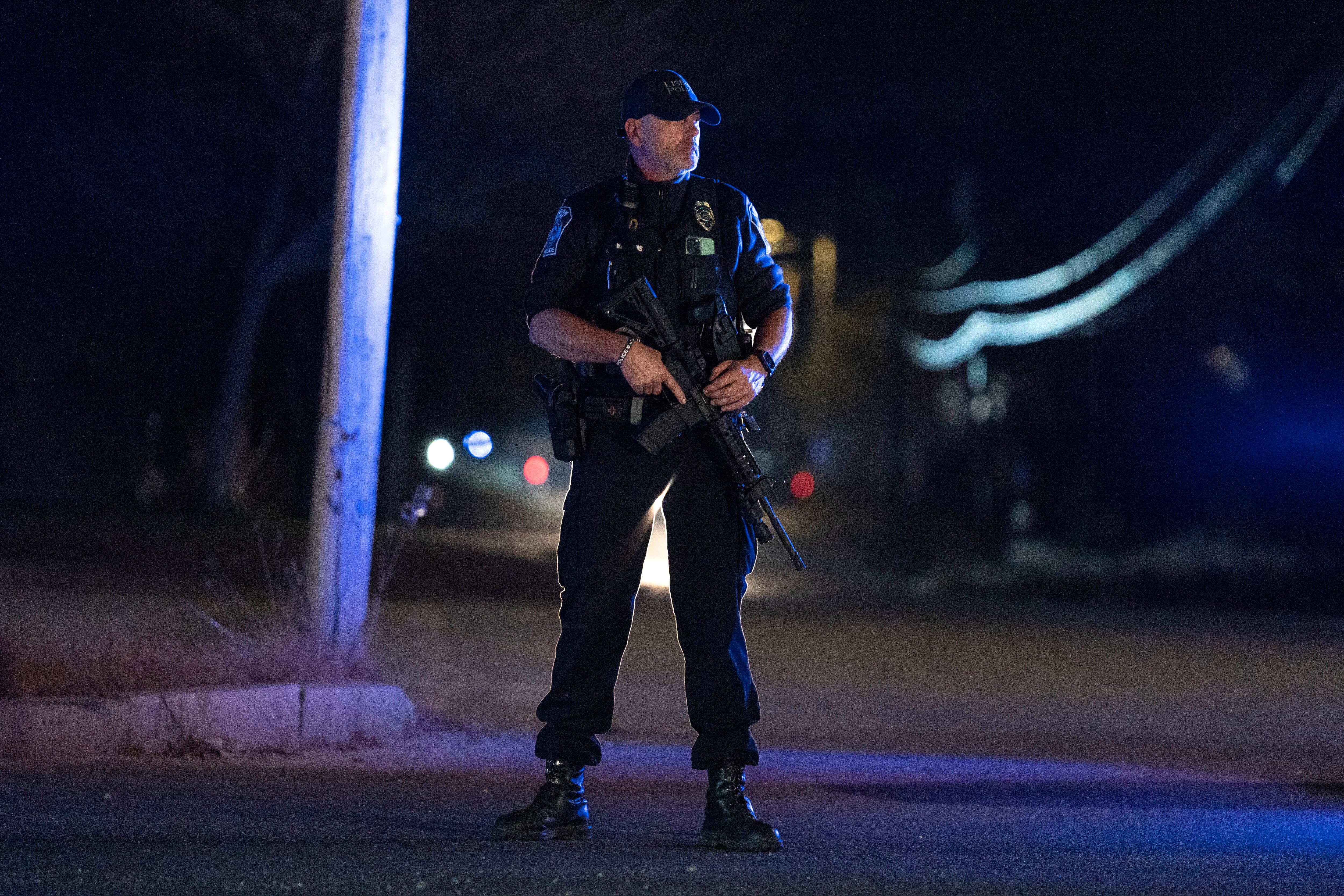 A police officer guards the road to a recycling facility where the body of Robert Card, the suspect in this week's mass shootings, was found, Friday, Oct. 27, 2023, in Lisbon, Maine.