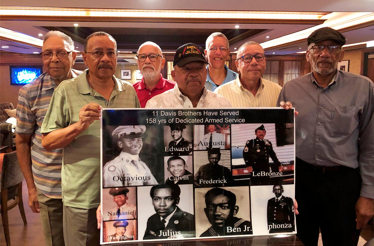 From the left: Eddie Davis and his brothers Julius, Octavious, Lebronze, Frederick, Arguster and Nathaniel, pose for a photo behind a family picture during a reunion at a hotel-casino on Friday, July 12, 2019 in Tunica, Miss.