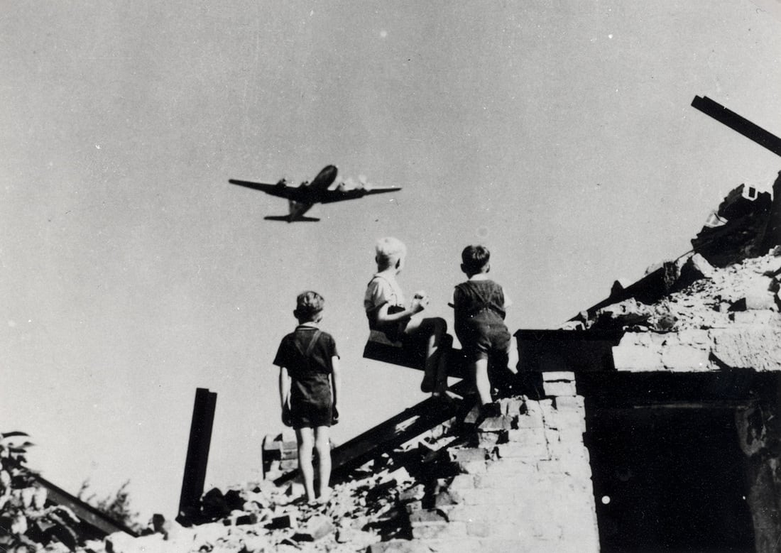 Children look on as a plane flies overhead. In 1948, the U.S. reportedly delivered some 13,000 tons of cargo and took off more than 89,000 times, totaling more than 600,000 hours of flight.