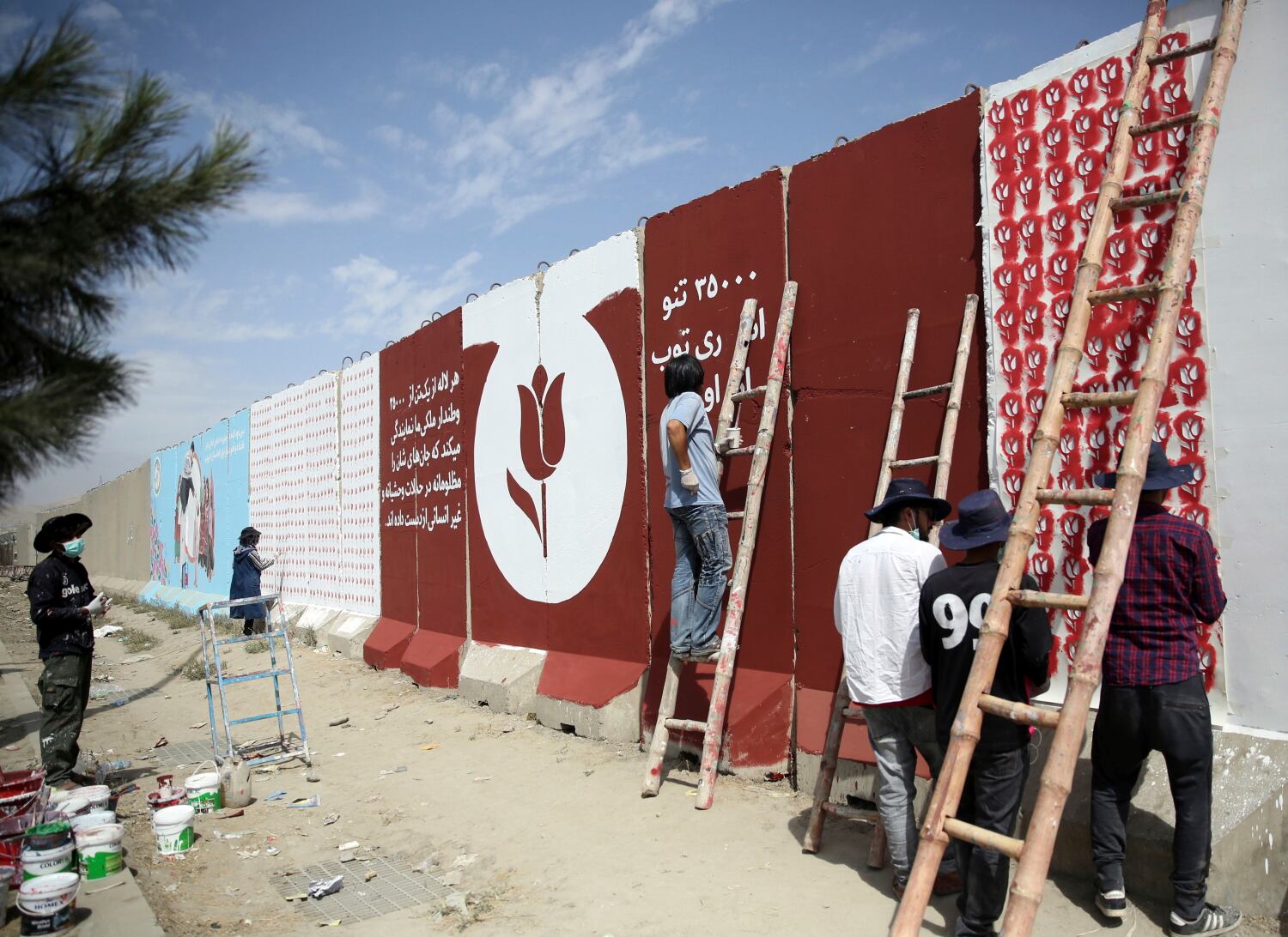 In this Friday, Aug. 30, 2019 photo, independent Afghan artists paints tulips on blast walls in Kabul, Afghanistan.