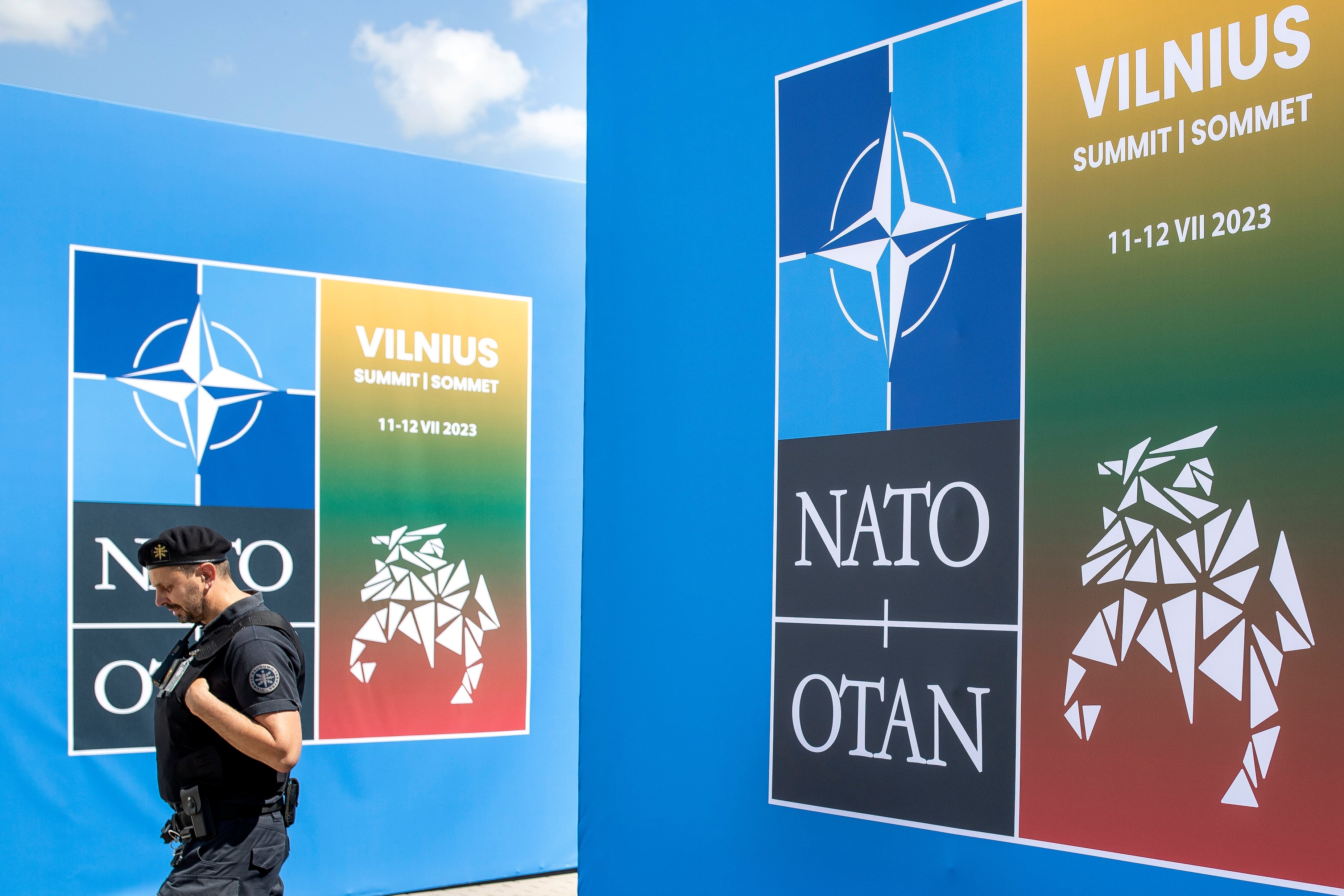 A security guard walks in front of a banner outside the venue of the NATO summit in Vilnius, Lithuania, Sunday, July 9, 2023.