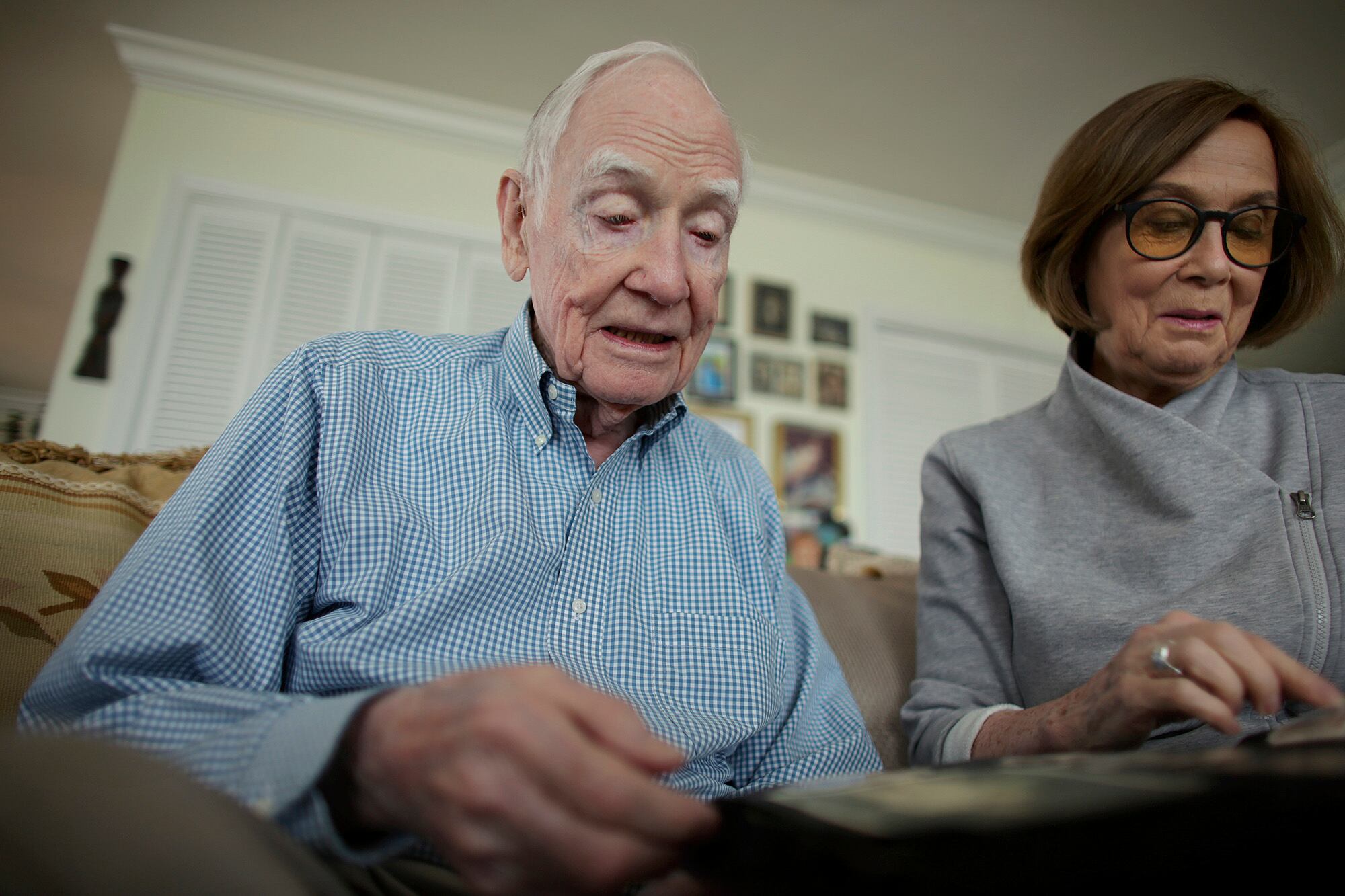 Veteran John Waller and his daughter Garland look through an album of photographs taken during his service in Europe during WWII, Thursday, Sept. 24, 2020, in Virginia Beach, Va.