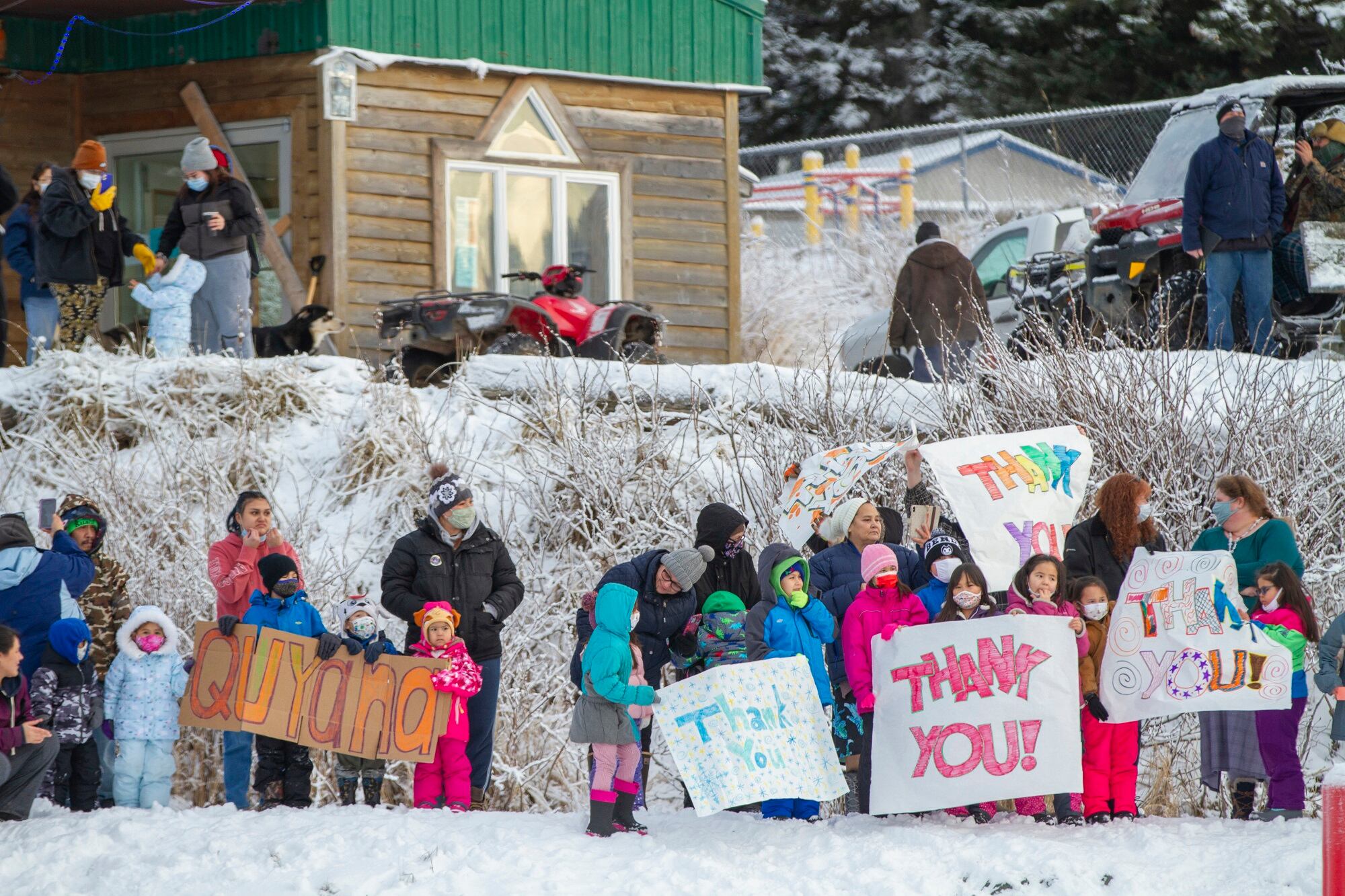 In this photo provided by the Alaska National Guard, residents of the village of Nanwalek, Alaska, greet guardsmen who delivered presents in a CH-47 Chinook helicopter during Operation Santa, Dec. 11, 2020.