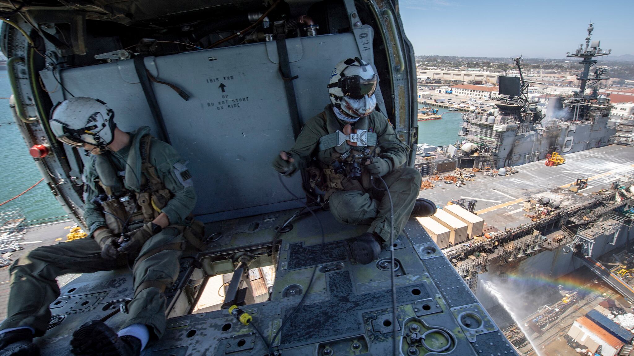 Naval Aircrewman (Helicopter) 2nd Class Ryan Siner, left, and Naval Aircrewman (Helicopter) 1st Class Jeremy Phillips utilize a Bambi bucket in an MH-60S Seahawk helicopter to provide aerial firefighting support to Wasp-class amphibious assault ship USS Bonhomme Richard (LHD 6) on July 14, 2020, in San Diego.