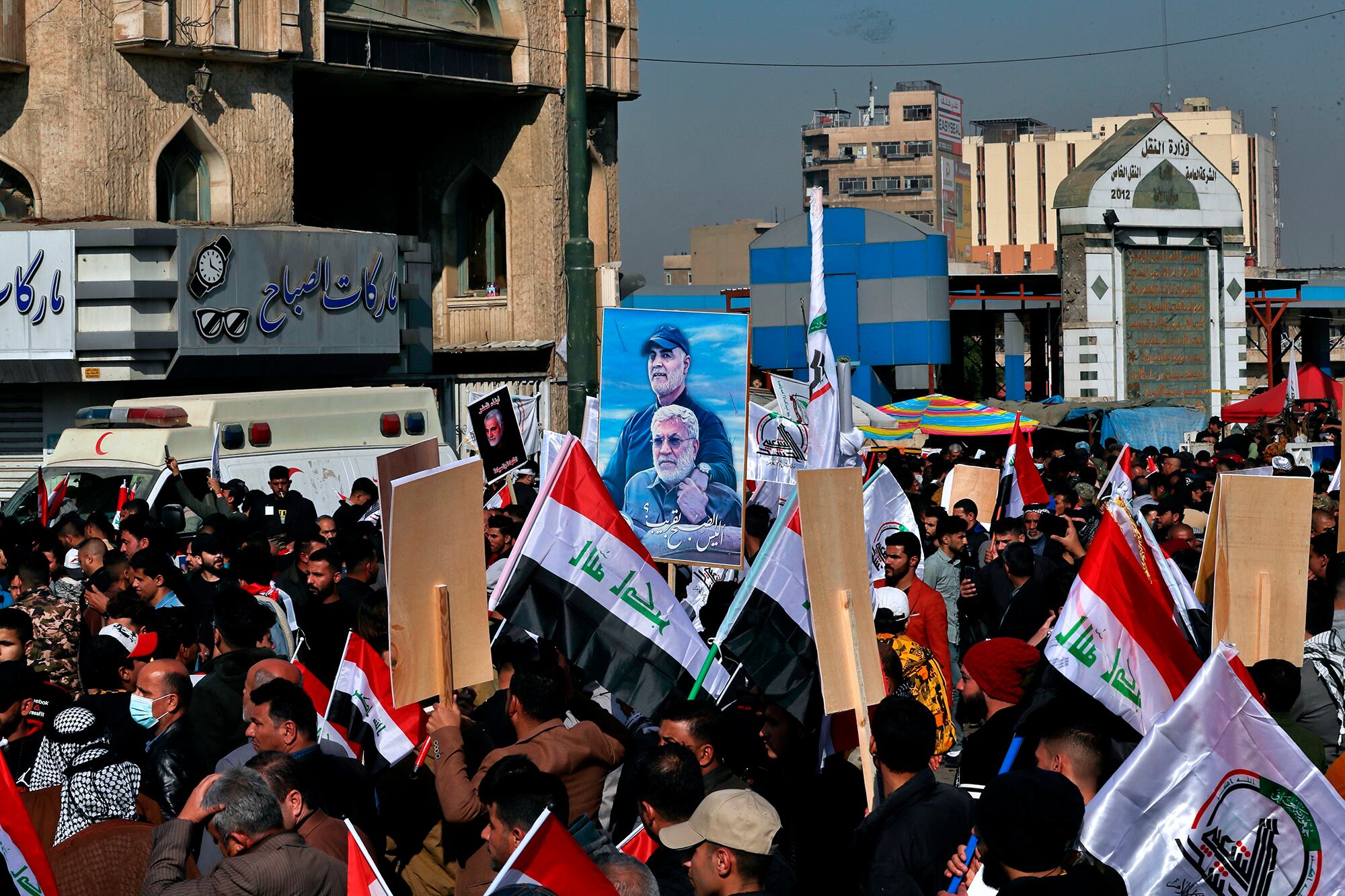 Supporters of the Popular Mobilization Forces hold a poster of Abu Mahdi al-Muhandis, deputy commander of the Popular Mobilization Forces, front, and Gen. Qassem Soleimani, head of Iran's Quds force during a protest, in Tahrir Square, Iraq, Sunday, Jan. 3, 2021.