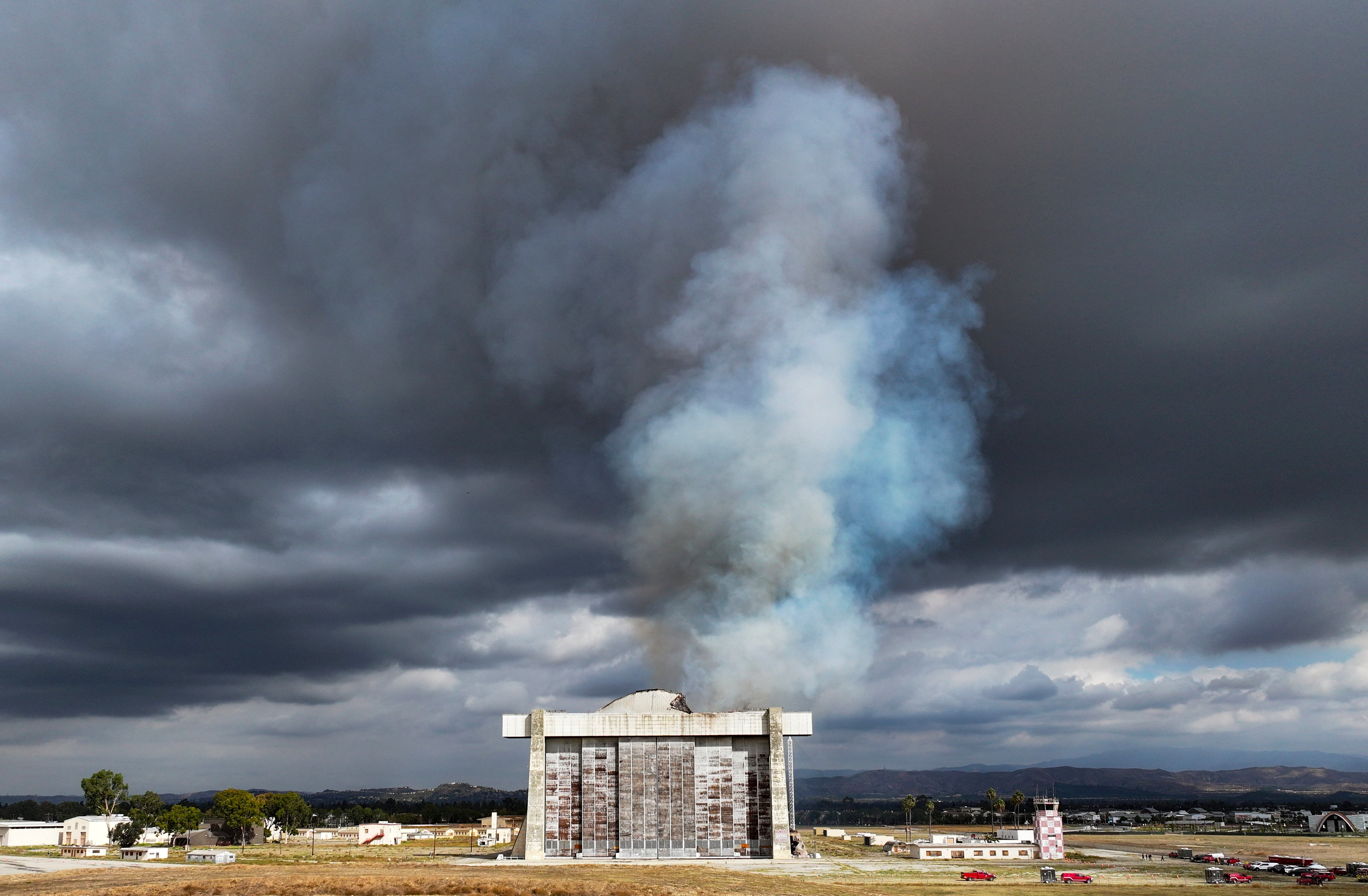 Firefighters work to control a blaze at the north blimp hangar at the former Marine Corps Air Station Tustin in Tustin, Calif., on Tuesday, Nov. 7, 2023.