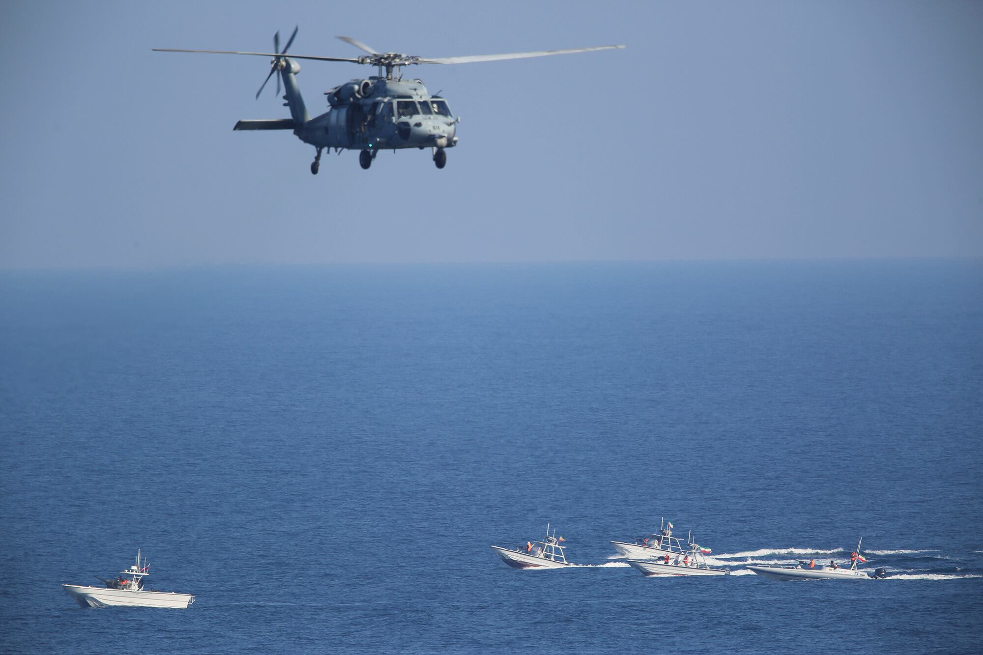 In this Dec. 21, 2018, file photo, a U.S. MH-60 Seahawk helicopter flies over Iranian Revolutionary Guard patrol boats in the Strait of Hormuz.