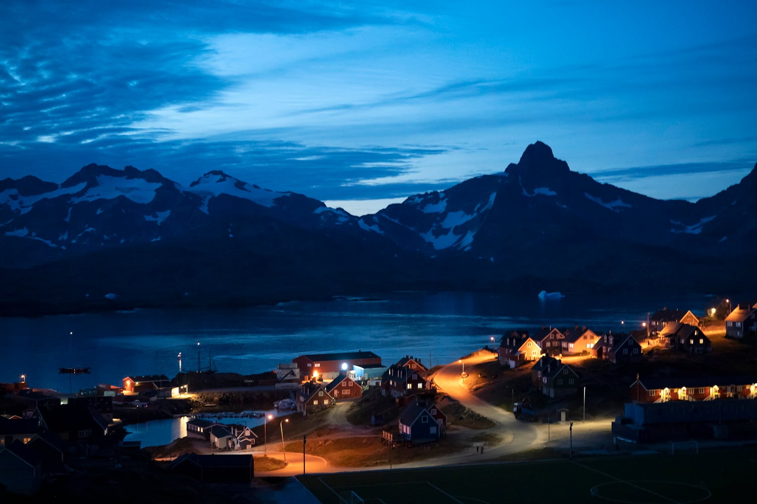 Homes are illuminated after the sunset in Tasiilaq, Greenland, late Friday, Aug. 16, 2019.