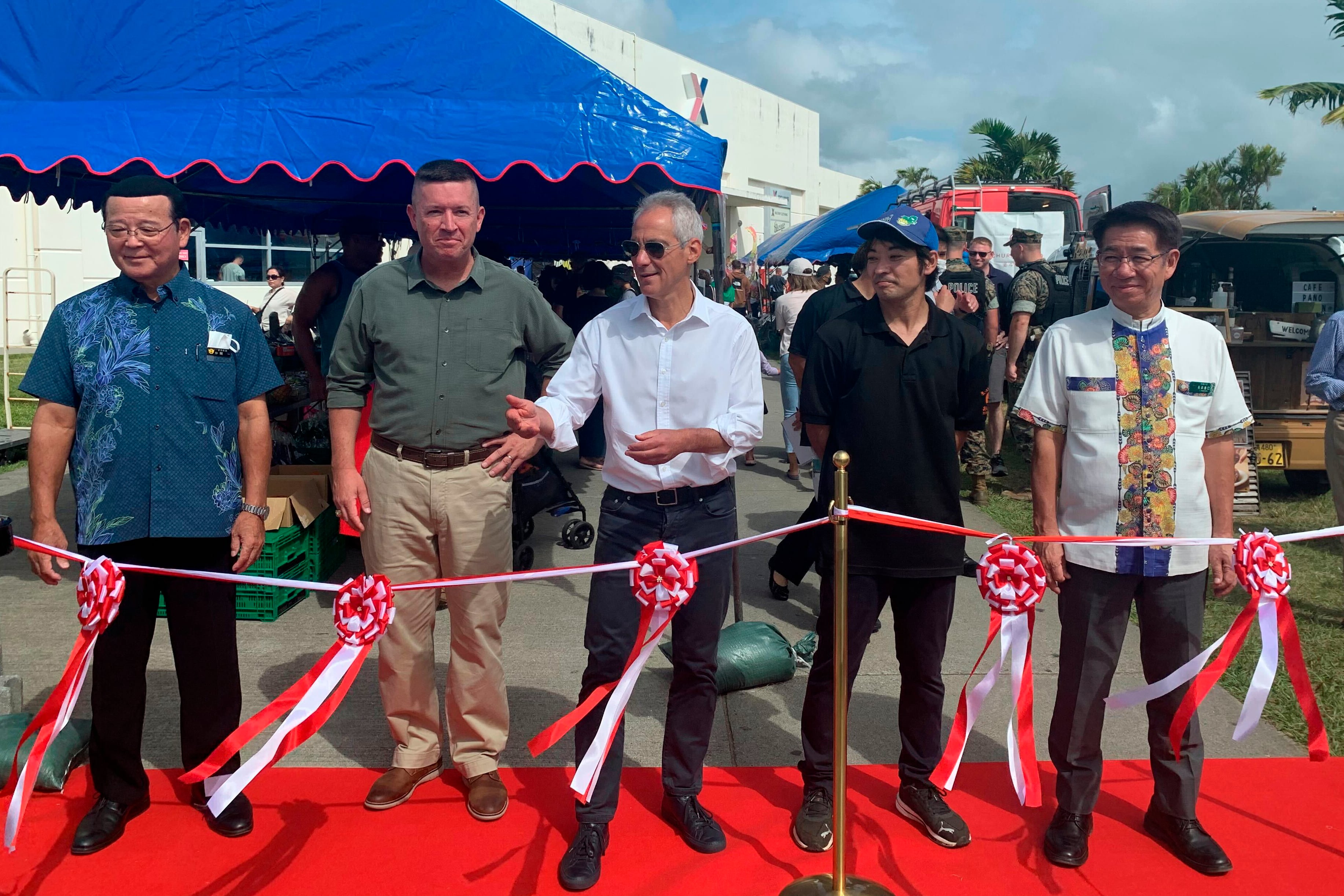 Okinawa's Kin town Mayor Hajime Nakama, from left, III Marine Expeditionary Force Commander Lt. Gen. James Bierman, U.S. Ambassador to Japan Rahm Emanuel, an unidentified local produce vendor from Onna village and Onna village Mayor Yoshimi Nagahama prepare to cut the ribbon on the farmers market at Camp Hansen, a U.S. Marine Corps base on a southern Japanese island of Okinawa, Sunday, Oct. 30, 2022.