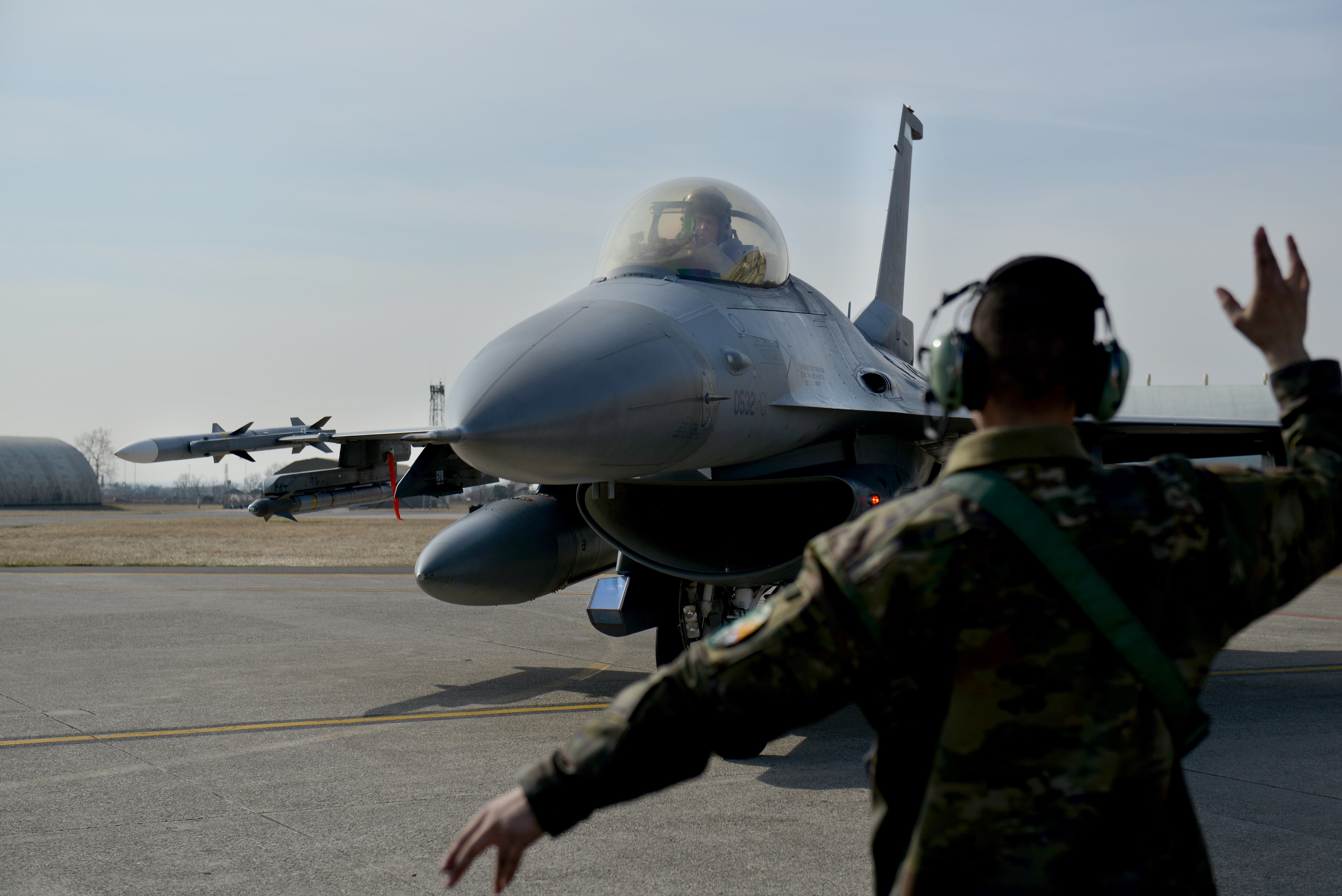 U.S. Air Force Airman 1st Class Jacob Wood, 31st Aircraft Maintenance Squadron assistant dedicated crew chief, marshals an F-16 Fighting Falcon aircraft assigned to the 555th Fighter Squadron at Aviano Air Base, Italy, Feb. 25, 2022. The flight will support NATO’s enhanced air policing mission; integrate with allies and partners in the Black Sea region in an increased defensive posture along NATO’s border and to reinforce regional security. (Natalie Stanley/Air Force)