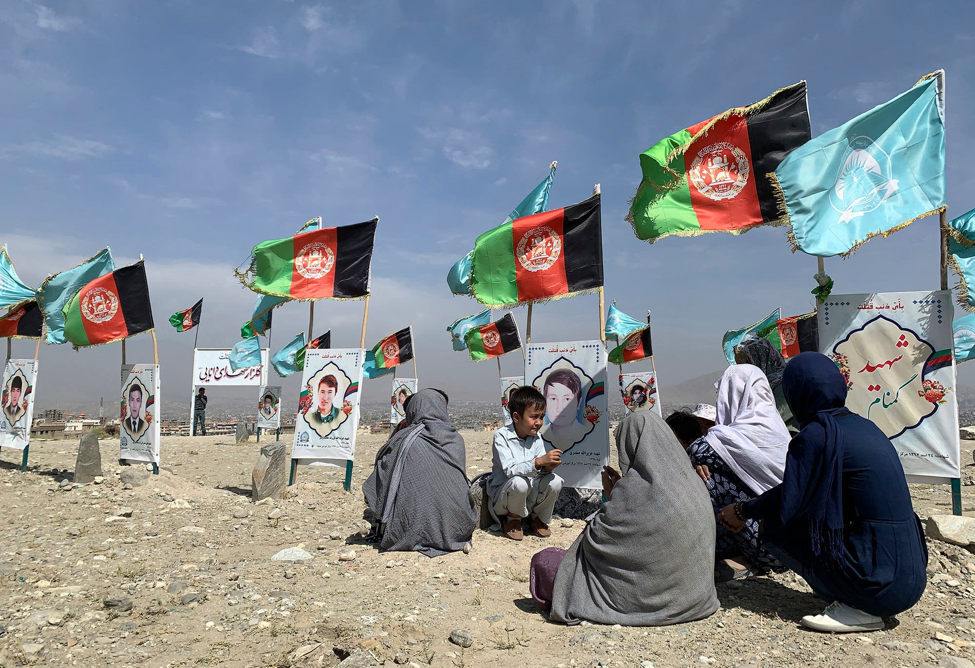 In this Sept 14, 2020, file photo, families gather at the graves of their relatives, adorned with their pictures, on the outskirts of Kabul, Afghanistan.