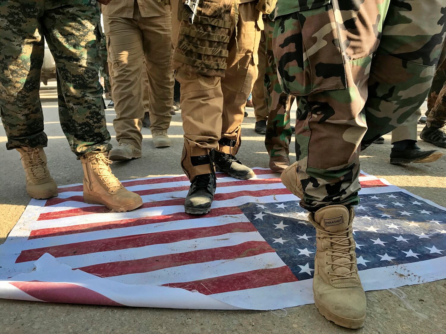 Mourners step over the print of a U.S. flag during the funeral procession of Abu Ali al-Dabi, a fighter of the Popular Mobilization Forces, during his funeral procession in Baghdad, Iraq, Monday, Aug. 26, 2019.