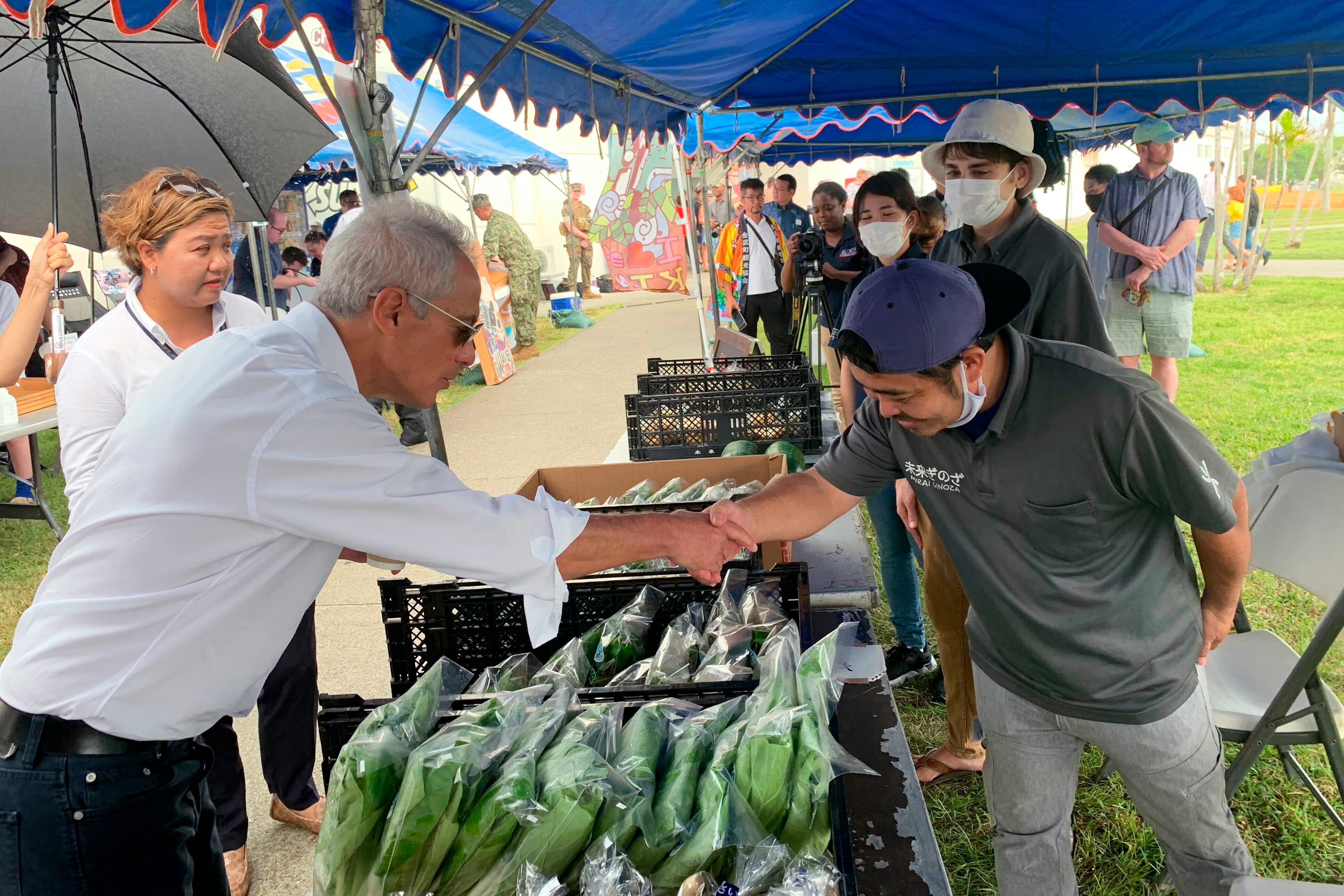 U.S. Ambassador to Japan Rahm Emanuel shakes hands with a local vendor at the farmers market at Camp Hansen, a U.S. Marine Corps base on a southern Japanese island of Okinawa, Sunday, Oct. 30, 2022.